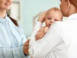 Regurgitacje i refluks żołądkowo-przełykowy u niemowląt dziecko u pediatry na rękach w trakcie rozmowy z opiekunką