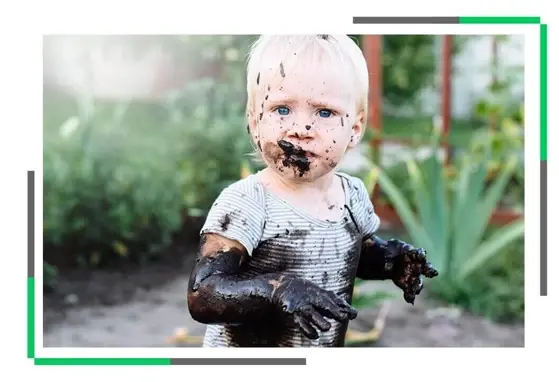 Mikrobiota - tajny sojusznik czy ukryty wróg? Dziecko ubrudzone błotem siedzące w ogrodzie